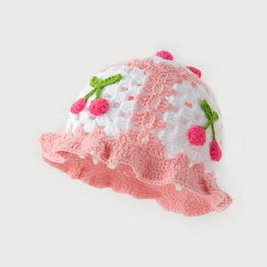 Detail of handmade knit bucket hat with cherry patterns and scalloped ruffle edge