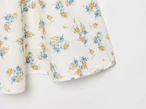 Détail d'une robe en popeline à imprimé floral bleu et jaune avec une finition soignée du bas