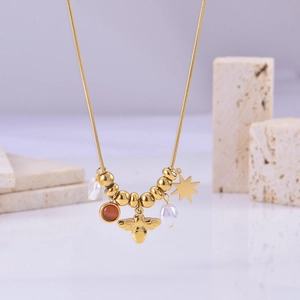 Macro view of gold snake chain with bee, star, pearls, and cat eye stone charms