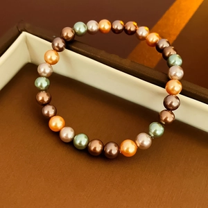 Vue macro de perles colorées sur un bracelet élastique posé sur une boîte à bijoux