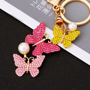 Close-up of butterfly keychains with colorful crystals, pearls and golden lobster clasp