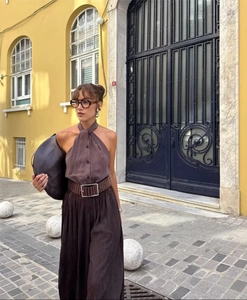 Outdoor street shot of women's dark brown halter top and pleated wide-leg trousers