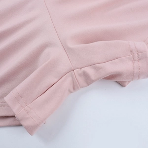 Close-up of pink knit fabric showing high-quality stitching and seam detail on a bodysuit