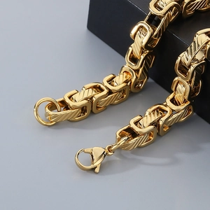 Macro detail of gold Byzantine chain featuring a sturdy lobster clasp and metallic luster