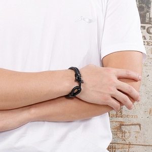 Gros plan d'un bracelet tressé noir pour homme avec un fermoir ancre en métal noir