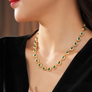 Détail d'un collier en or avec pendentif ovale émeraude porté par un mannequin