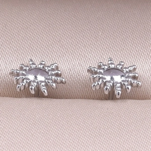 Macro shot of sun-shaped 304 stainless steel stud earring on champagne silk
