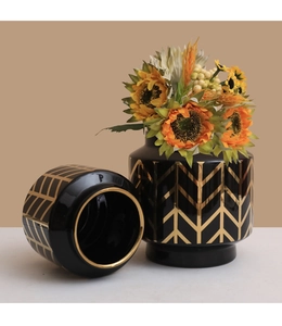 Dettaglio di vasi in ceramica nera con motivi a freccia dorati e accenti di girasole