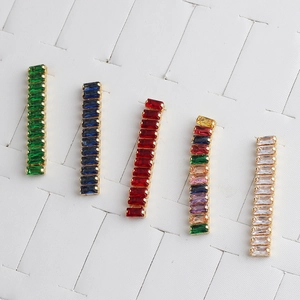 Flat lay of colorful rectangular crystal earrings with gold plating on white background
