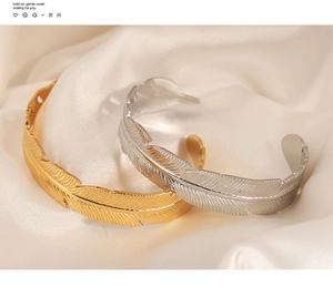 Macro shot of gold and silver feather-shaped open bangles on silk background