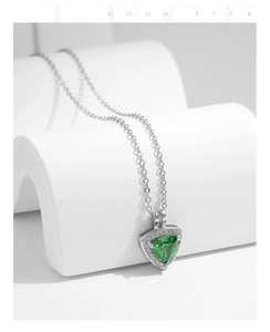 Macro view of a geometric triangle pendant with emerald green stone on white props
