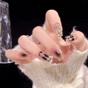 Detail of glitter checkerboard press-on nails with rhinestone accents and ombre design
