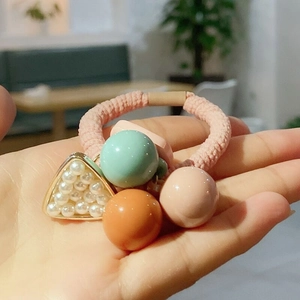 Detail of pink hair tie featuring macaron beads and a pearl-inlaid triangle charm