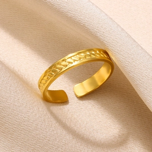 Close-up of golden adjustable ring with wheat-pattern embossed texture on silk background