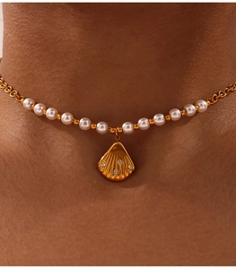Detail of pearl and gold bead necklace with a diamond-encrusted shell pendant on model