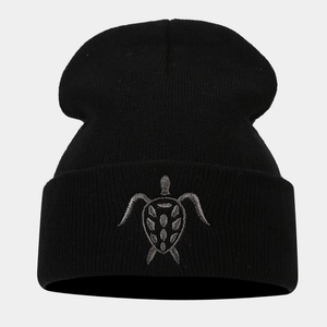 Close-up of turtle embroidery on a black knitted beanie with high-quality stitching details