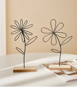 Detail view of black iron wire flower ornaments with minimalist wooden base on a white desk