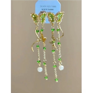 Détail de boucles d'oreilles papillon en argent S925 avec longs pompons verts et perle