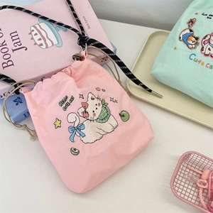 Detail of pink and mint green drawstring bags with cute cat embroidery and cord closure