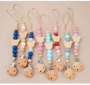 Flat lay of eight colorful silicone and wooden pacifier clips with bear-shaped wood beads