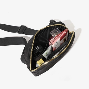 Minimalist black waist bag with gold zipper and organized interior storage compartments