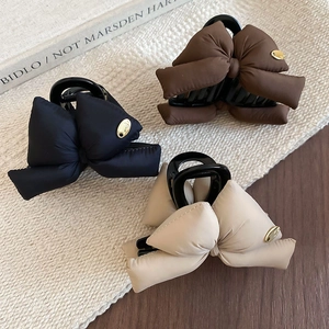 Detailed view of padded bow claw clips in black, brown and beige with gold metal accents