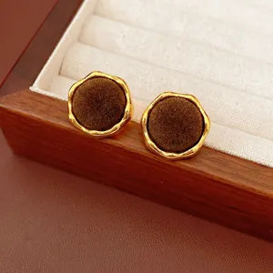 Vintage gold wavy earrings with dark brown velvet center on a luxury jewelry box