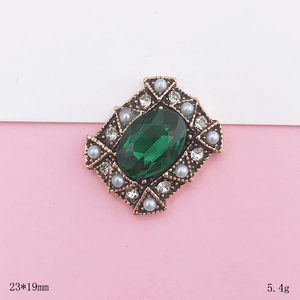 Makro-Detail einer 23x19mm Vintage-Brosche mit grünem Edelstein und Perlenbesatz