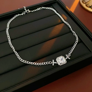 Détail macro du collier chaîne gourmette en argent avec zircon carré et pendentifs croix