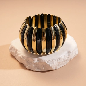 Macro shot of gold-plated metal and black acrylic chunky elastic bead bracelet on stone
