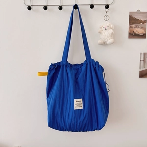 Detailed view of blue pleated tote bag featuring drawstring closure and brand label