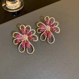 Detailed view of rose red and clear crystal floral earrings with hollow gold metal design