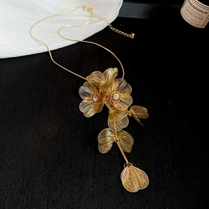 Detail view of golden floral pendant with hollow design, sparkling crystals, and tassels