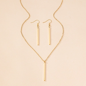 Flat lay of a gold geometric rectangular necklace and matching drop earrings on beige background