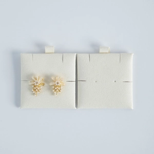 Detailed macro view of floral stud earrings with pearls and crystals on card