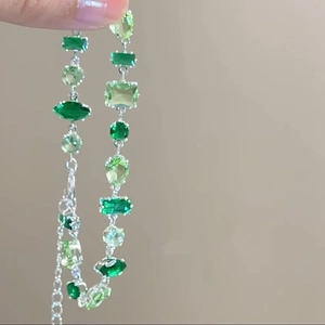 Handheld silver bracelet with mixed-cut green stones and adjustable extension chain