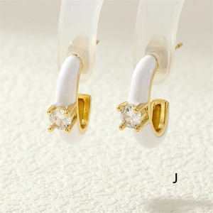 Macro shot of C-shaped white enamel earring with gold finish and central zircon stone