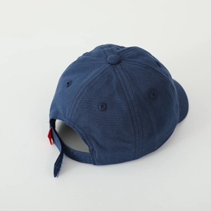 Detail of adjustable velcro strap and red tag on navy blue cotton baseball cap for kids