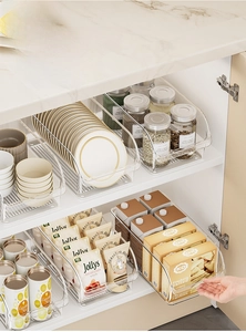 Detail view of transparent acrylic kitchen organizers for snacks and bottles in white cabinets