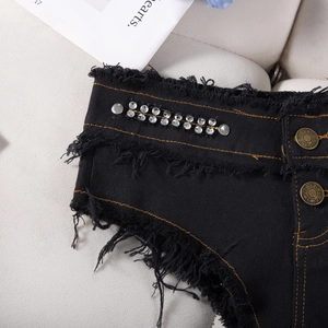 Vista dettagliata degli shorts di jeans neri con borchie di strass e bottoni in metallo