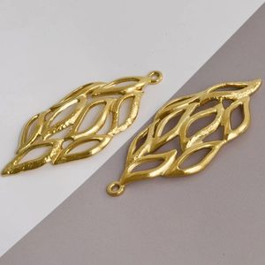 Detailed macro view of two hollow leaf-shaped pendants with hammered gold metal texture