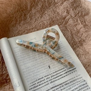 Detailed view of large marble acetate hair claw clip with golden metal inner teeth
