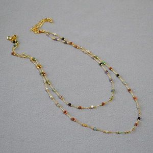 Detail view of double-layer gold chain necklace with colorful small stone beads