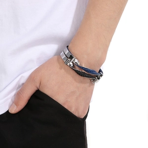 Macro detail of men's multi-layer black and blue braided rope bracelet with silver clasp