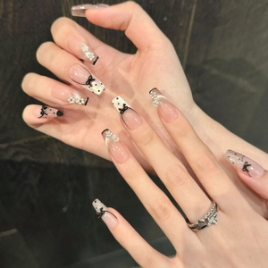 Detail of long coffin press-on nails featuring black bows, pearls, and polka dot patterns