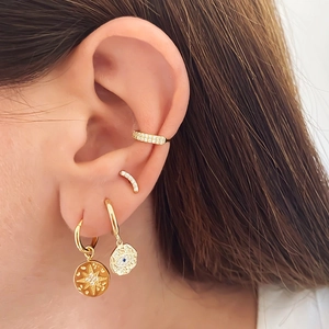 Close-up of gold moon and sun star earrings set with cubic zirconia on female ear