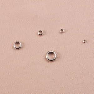 Polished silver stainless steel rings and jewelry making beads on pink fabric