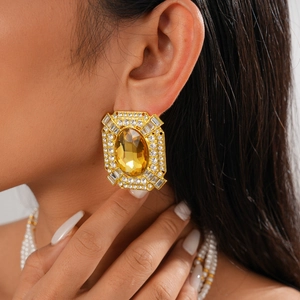 Close-up of vintage geometric gold earrings with amber resin and sparkling crystals