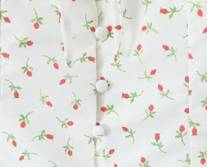 Close-up of floral print fabric with delicate red flowers and white fabric-covered buttons