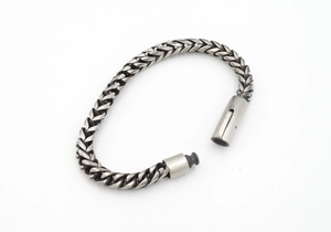Detailed close-up of a silver stainless steel braided chain bracelet with a secure plug-in clasp